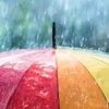 Colorful umbrella with red, orange, yellow, and green panels under heavy rain, symbolizing weather protection and durability